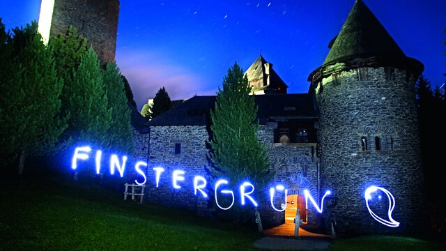 Nachtaufnahme der Burg mit Neon schrift Finstergrün - Foto: Ackerl